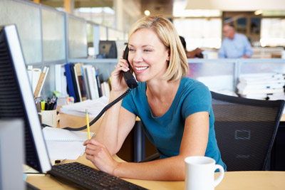Business woman on phone at her desk. America's Phone Guys 4 Ways to Keep Your VoIP Service from Suffering with Internet Issues in the Portland OR and Vancouver WA areas.